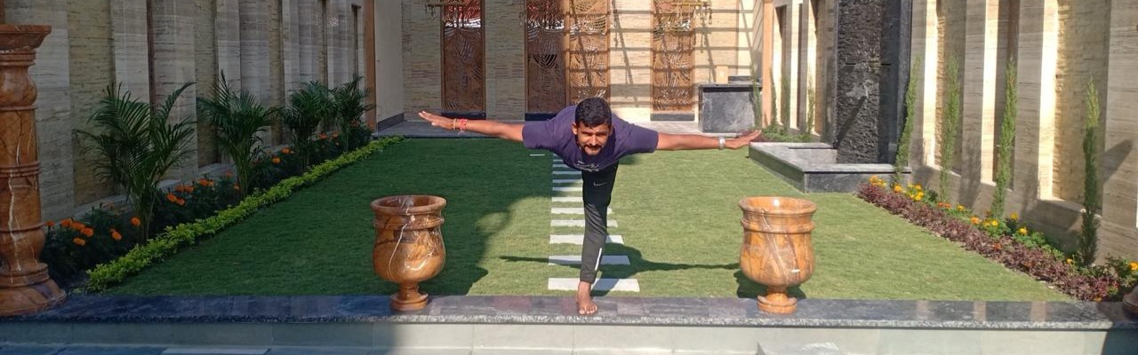 Guru Pant holding warrior three pose in a stone courtyard in Kathmandu